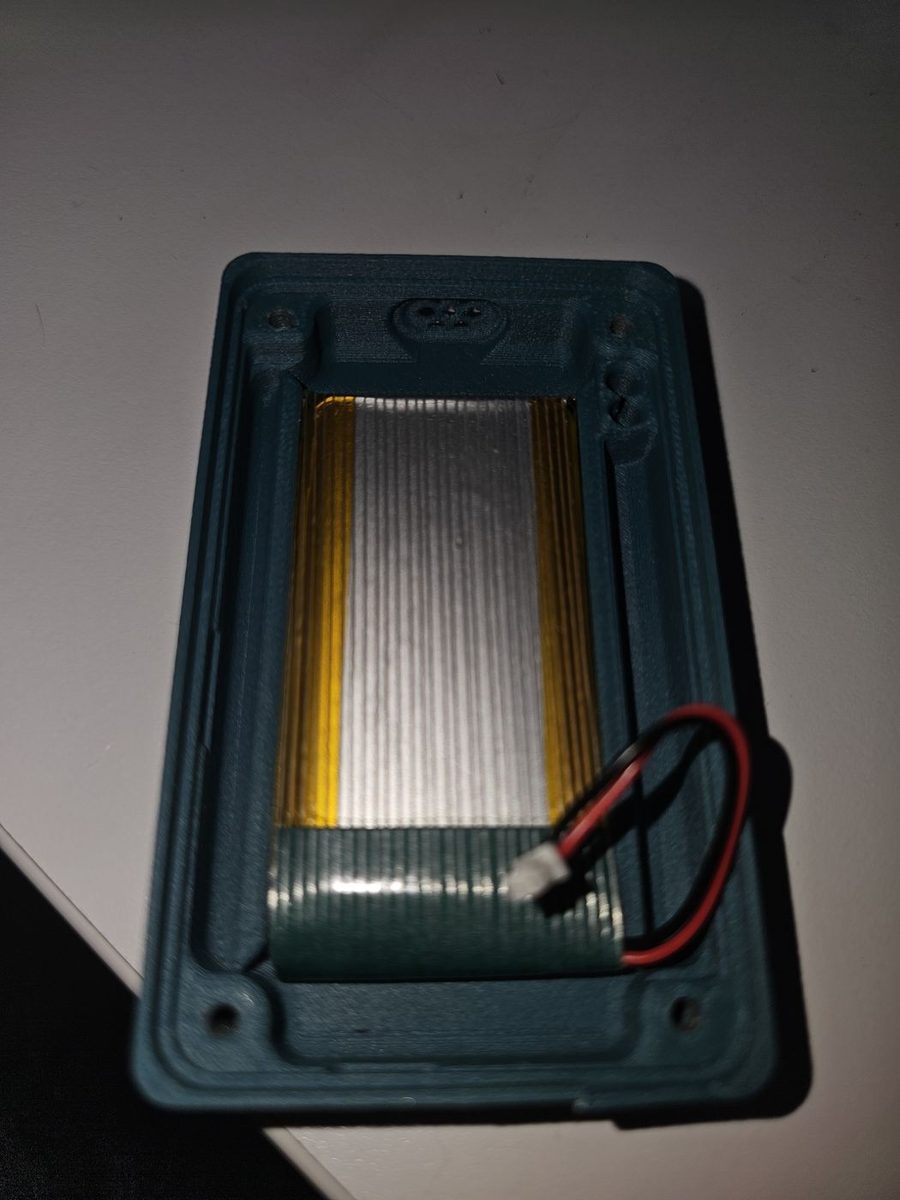 The 3000 mAh battery seated in the bottom half of the printed case, with its red and black wire routed towards the side of the case with the buttons.