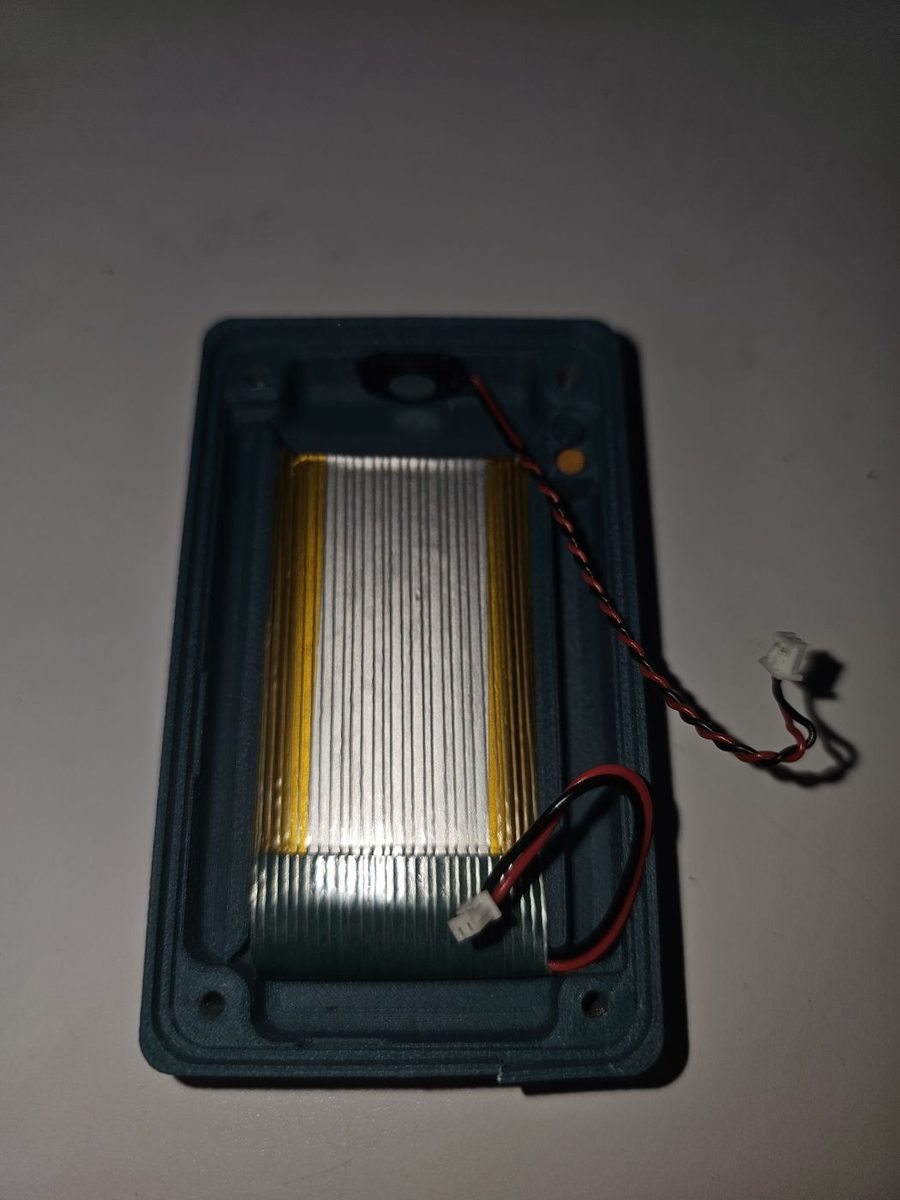 The printed base with the battery fitted and the small speaker pressed into its slot at the top, both wires loose and ready to plug in.