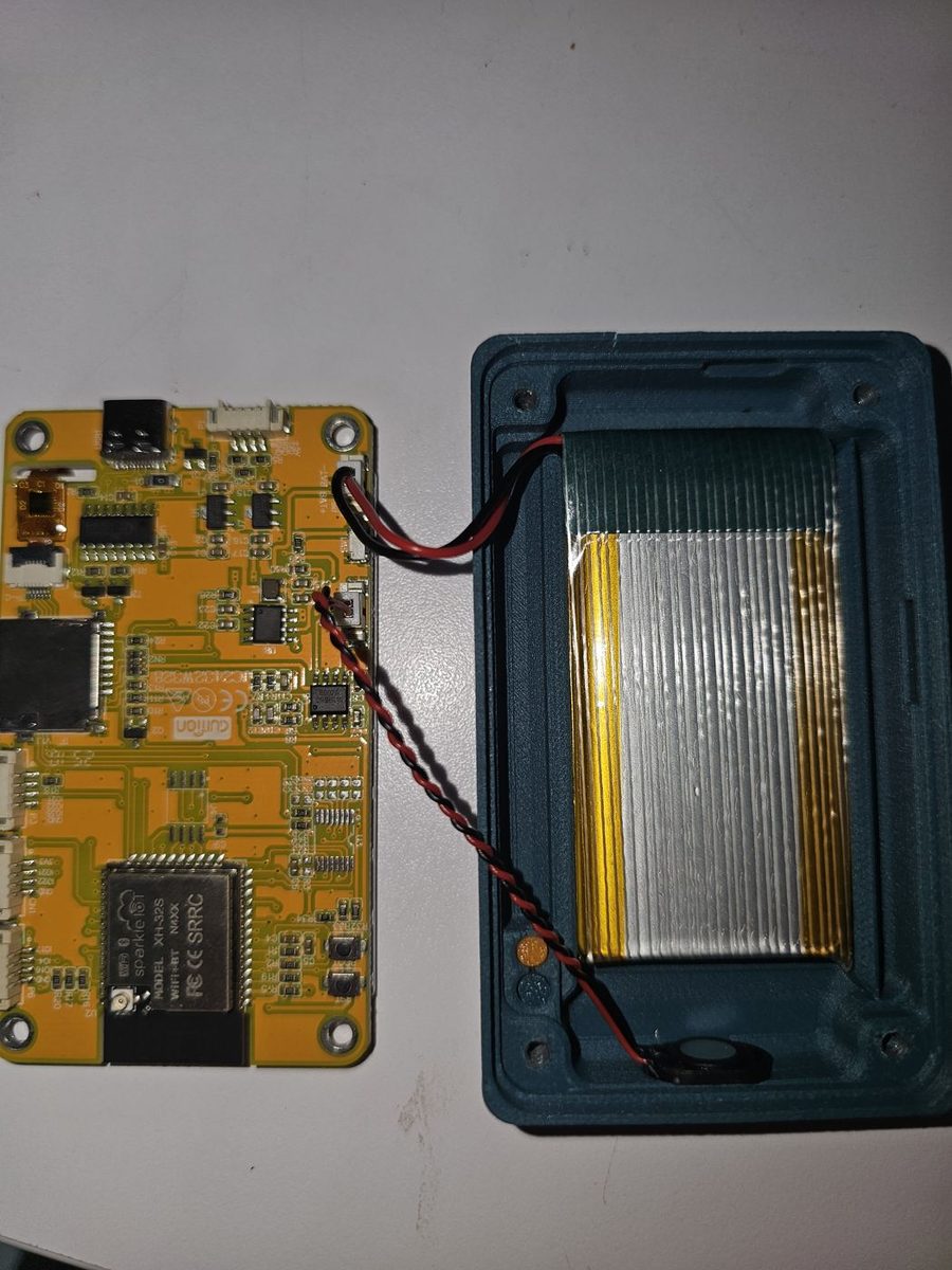 The ESP32 display board lying next to the printed base, with the battery and speaker leads running across to their connectors on the board.