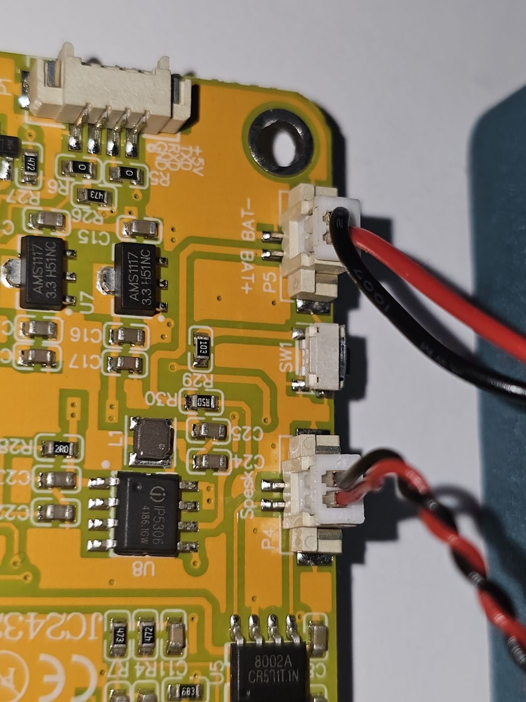 Close-up of the board showing two nearly identical white connectors. The upper one is labelled BAT minus and BAT plus on the silkscreen and holds the battery lead. The lower one is labelled Speak and holds the speaker lead.