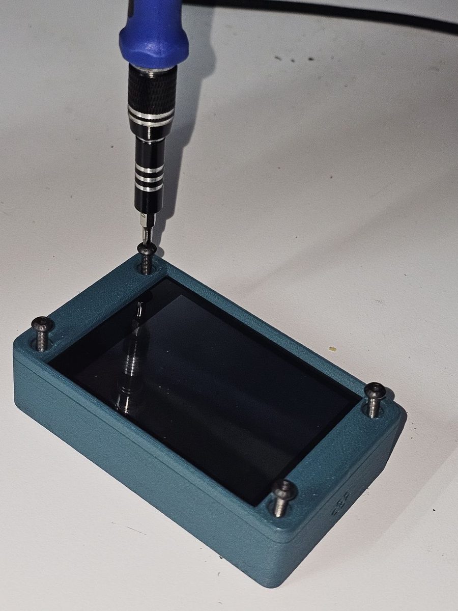 A small screwdriver driving one of four M3 button head screws into a corner of the assembled case.